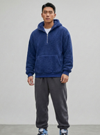 Person wearing a blue hoodie and gray sweatpants on a plain background
