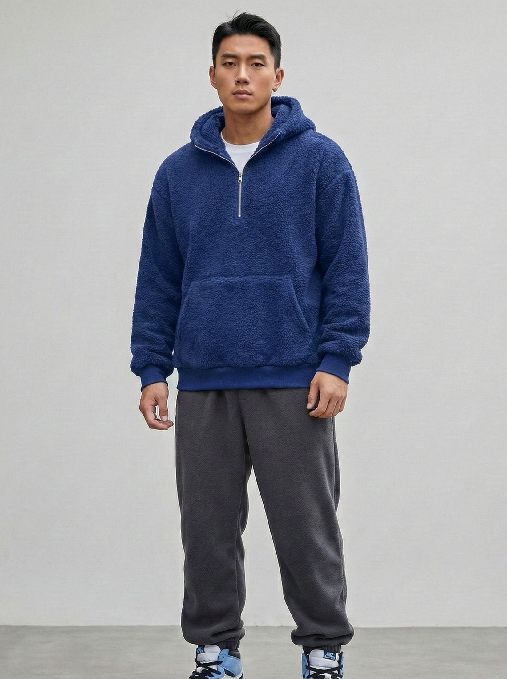 Person wearing a blue hoodie and gray sweatpants on a plain background